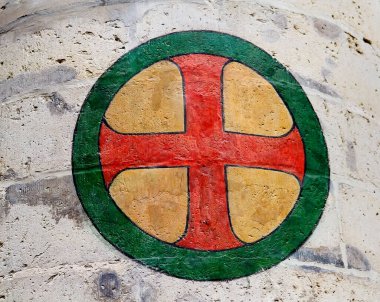 Sert beton duvara çizilmiş dairesel haç sembolü kalın renkler yıpranmış grafik yüzey ve kentsel doku yaratıyor.