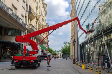 Budapeşte, Macaristan - 3 Ağustos 2018: Kırmızı vinç şehir caddesinde işçi temizleme cam binası, kentsel çevrede inşaat bakımı