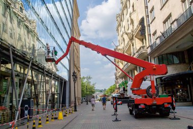 Budapeşte, Macaristan - 3 Ağustos 2018: Kırmızı vinç şehir caddesinde işçi temizleme cam binası, kentsel çevrede inşaat bakımı