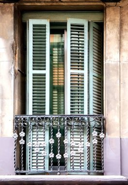 Eski apartman penceresi, yeşil ahşap panjurlar ve dekoratif demir balkon nostaljik şehir mimarisini yansıtıyor.