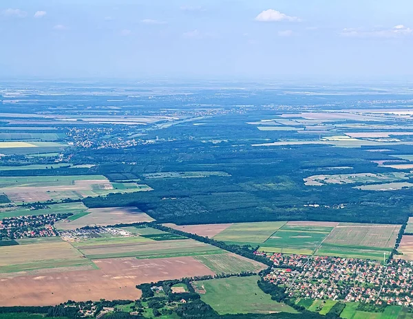 Yoğun orman tarlaları ve kırsal yolları gösteren eğimli hava manzarası orman ve ekili arazi arasında güçlü bir zıtlık yaratıyor.