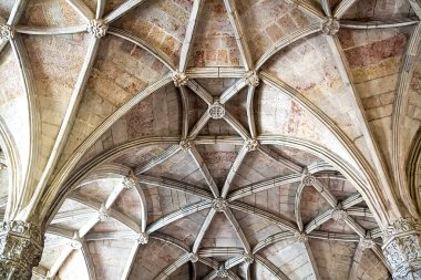 Karmaşık taş kubbeli tavanın detaylı bir görüntüsü. Tarihi bir yapıda tırtıklı kemerler, çiçek patronları ve oyulmuş sütunlar. Mimari miras, turizm pazarlaması, iç tasarım ve lüks markalaşma uygulamaları için ideal