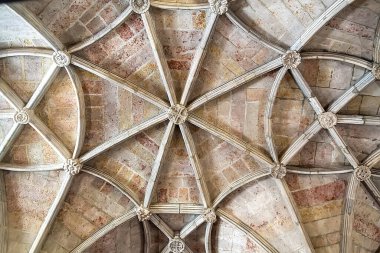Karmaşık taş kubbeli tavanın detaylı bir görüntüsü. Tarihi bir yapıda tırtıklı kemerler, çiçek patronları ve oyulmuş sütunlar. Mimari miras, turizm pazarlaması, iç tasarım ve lüks markalaşma uygulamaları için ideal