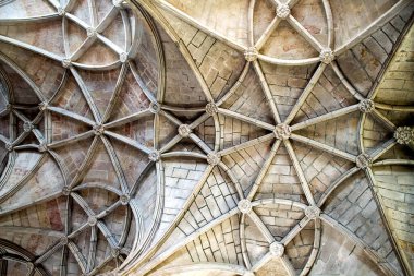 Karmaşık taş kubbeli tavanın detaylı bir görüntüsü. Tarihi bir yapıda tırtıklı kemerler, çiçek patronları ve oyulmuş sütunlar. Mimari miras, turizm pazarlaması, iç tasarım ve lüks markalaşma uygulamaları için ideal