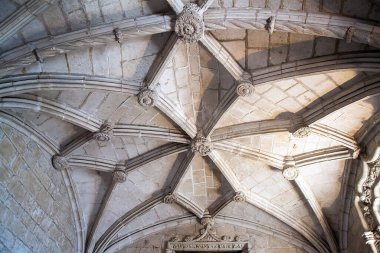 Karmaşık taş kubbeli tavanın detaylı bir görüntüsü. Tarihi bir yapıda tırtıklı kemerler, çiçek patronları ve oyulmuş sütunlar. Mimari miras, turizm pazarlaması, iç tasarım ve lüks markalaşma uygulamaları için ideal