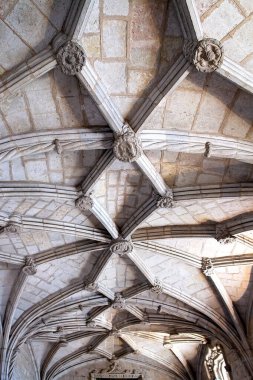 Karmaşık taş kubbeli tavanın detaylı bir görüntüsü. Tarihi bir yapıda tırtıklı kemerler, çiçek patronları ve oyulmuş sütunlar. Mimari miras, turizm pazarlaması, iç tasarım ve lüks markalaşma uygulamaları için ideal