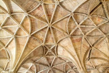 Karmaşık taş kubbeli tavanın detaylı bir görüntüsü. Tarihi bir yapıda tırtıklı kemerler, çiçek patronları ve oyulmuş sütunlar. Mimari miras, turizm pazarlaması, iç tasarım ve lüks markalaşma uygulamaları için ideal