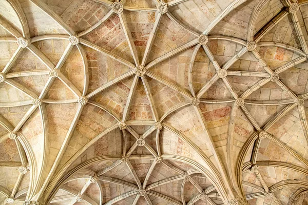 Karmaşık taş kubbeli tavanın detaylı bir görüntüsü. Tarihi bir yapıda tırtıklı kemerler, çiçek patronları ve oyulmuş sütunlar. Mimari miras, turizm pazarlaması, iç tasarım ve lüks markalaşma uygulamaları için ideal
