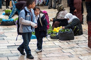 Israel, Jerusalem - 24 Mar 2011: Local residents, including women in headscarves, sell fresh produce like greens and vegetables from the ground or small trays at the popular Mahane Yehuda Market, offering a glimpse into Jerusalems daily life