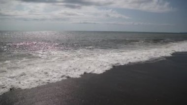 Sahilde köpükle dalgalanan deniz dalgalarının görüntüleri.