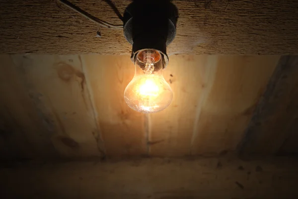 Vecchia lampada che brucia su un soffitto di legno — Foto Stock