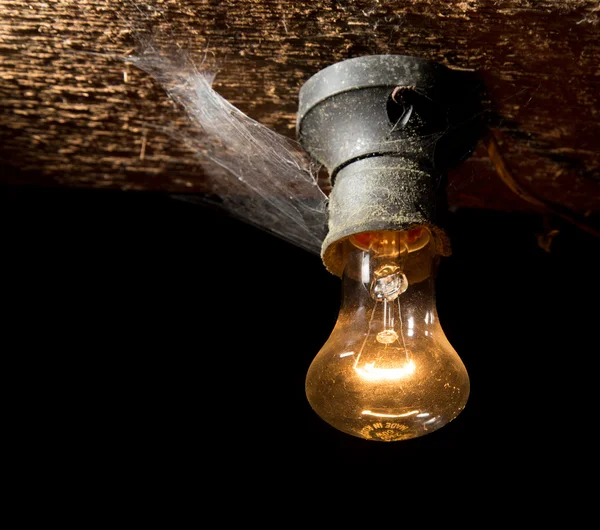 Lâmpada velha queimando em um teto de madeira — Fotografia de Stock