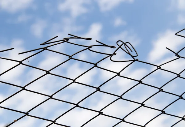Fém kerítés ellen a kék ég, a felhők — Stock Fotó