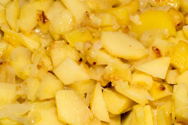 Aardappelen en uien in een koekenpan als achtergrond — Stockfoto