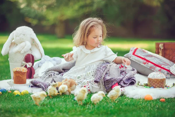 A criança senta-se em um prado em volta da decoração de Páscoa — Fotografia de Stock