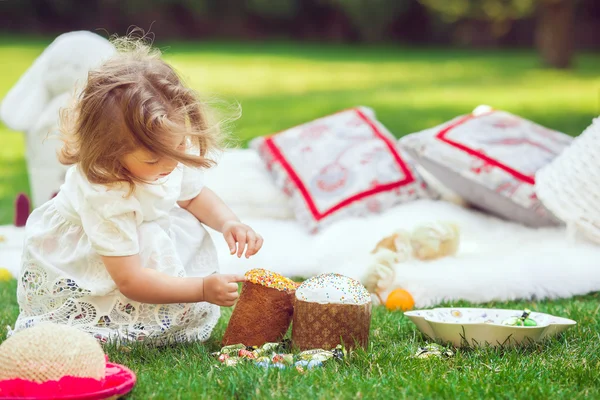 Glückliches Kind sitzt auf einer Wiese mit Osterdekoration — Stockfoto