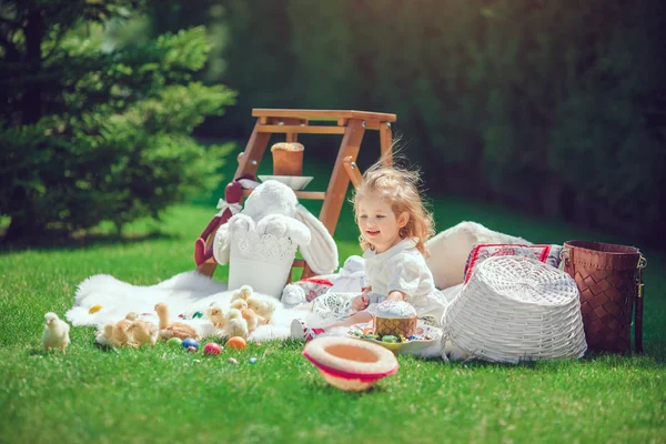 Criança feliz senta-se em um prado em torno da decoração de Páscoa — Fotografia de Stock