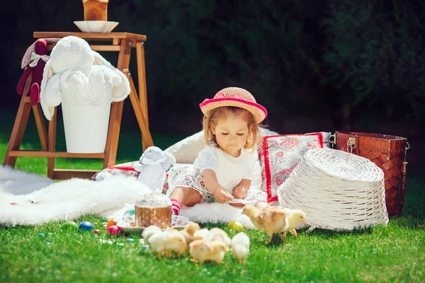 A criança senta-se em um prado em volta da decoração de Páscoa — Fotografia de Stock