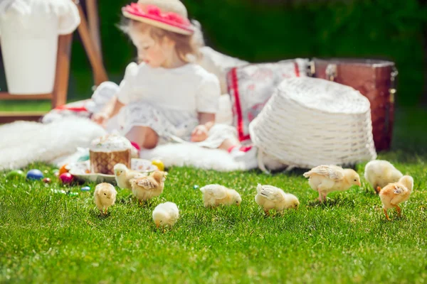 Child sits on a meadow around Easter decoration — Stock Photo, Image