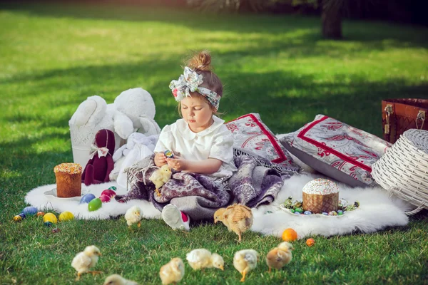 Ребенок сидит на лугу вокруг пасхального украшения — стоковое фото