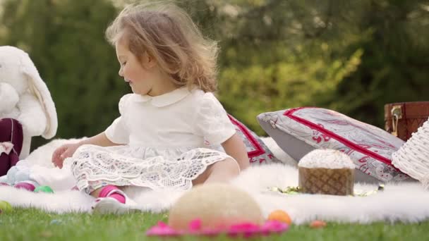 Bambino felice si siede su un prato intorno alla decorazione di Pasqua — Video Stock