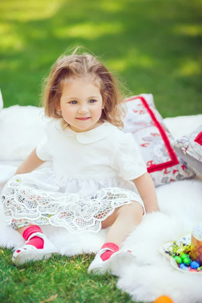 Щаслива дитина сидить на лузі навколо Великодня прикраси — стокове фото