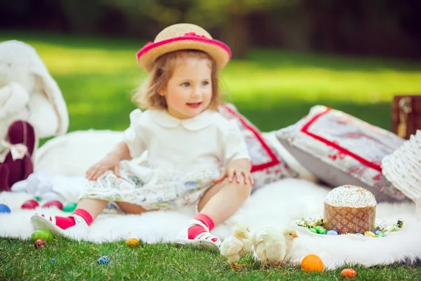 Glückliches Kind sitzt rund um Osterdekoration auf einer Wiese — Stockfoto