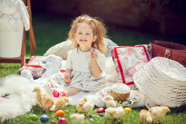 Glückliches Kind sitzt rund um Osterdekoration auf einer Wiese — Stockfoto