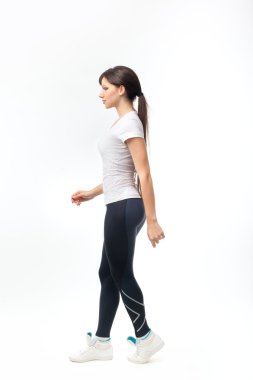 Beyaz arka plan üzerinde yürüyen genç bir kadın tam uzunlukta