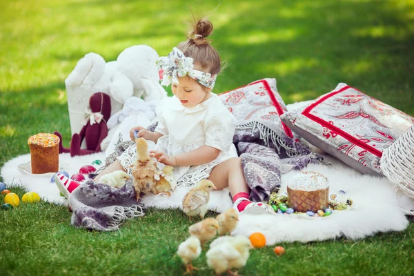 Glückliches Kind sitzt rund um Osterdekoration auf einer Wiese — Stockfoto