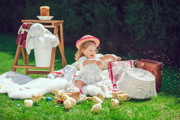 Criança feliz senta-se em um prado em torno da decoração de Páscoa — Fotografia de Stock