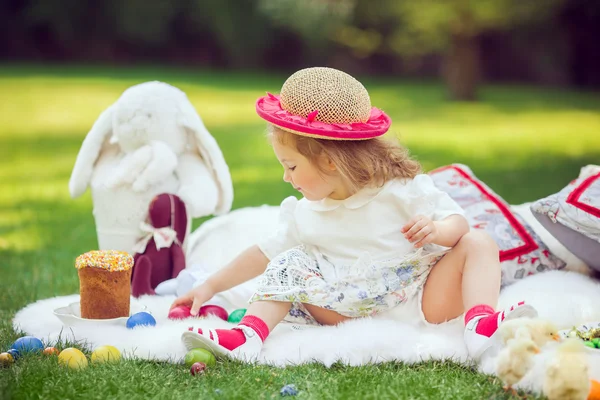 Criança feliz senta-se em um prado em torno da decoração de Páscoa — Fotografia de Stock