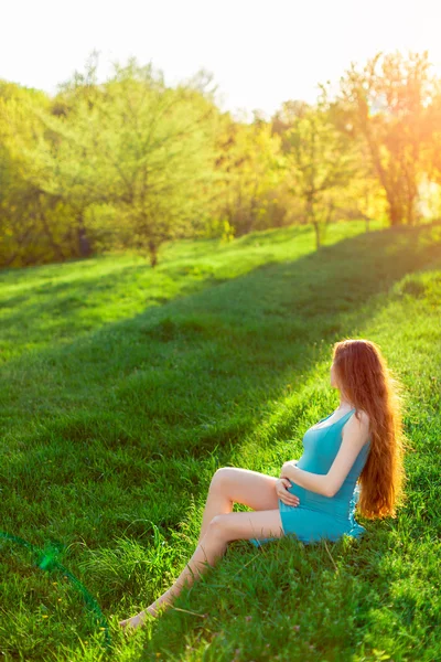 Schöne schwangere Frau im Garten. Sonnenuntergang oder Sonnenaufgang — Stockfoto