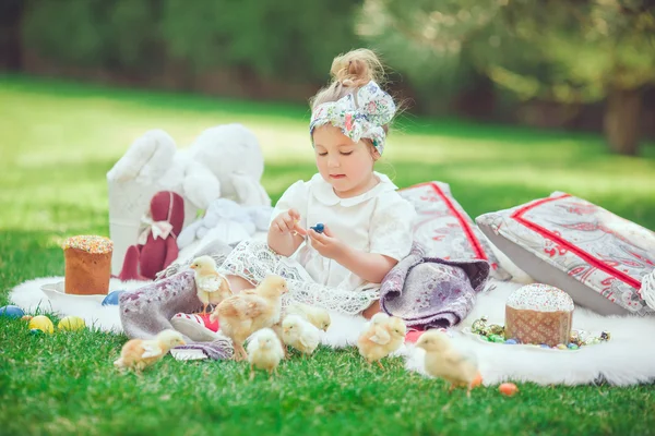 A criança feliz senta-se em um prado olha para a decoração de Páscoa — Fotografia de Stock