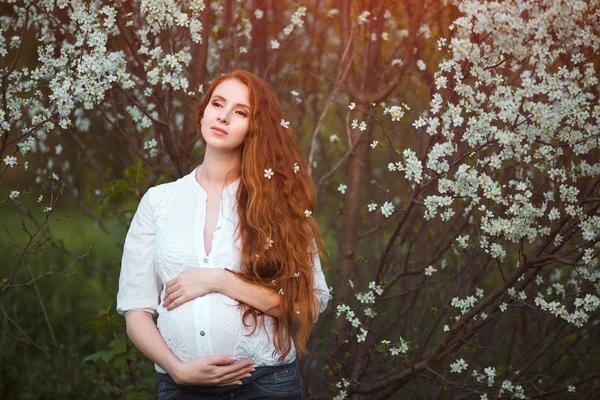 Vacker gravid kvinna i blommande trädgård — Stockfoto