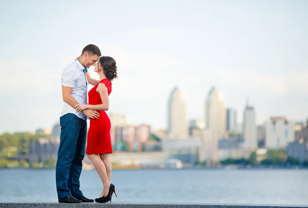 Feliz joven pareja abraza contra la ciudad — Foto de Stock