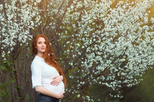 Schöne schwangere Frau im blühenden Garten — Stockfoto