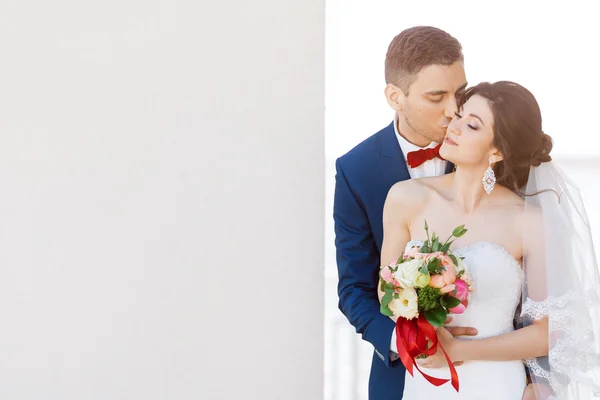 灰色の壁を付近の若者の結婚式のカップルのキス — ストック写真