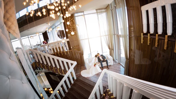 Young wedding couple on sofa against a window — Stock Photo, Image