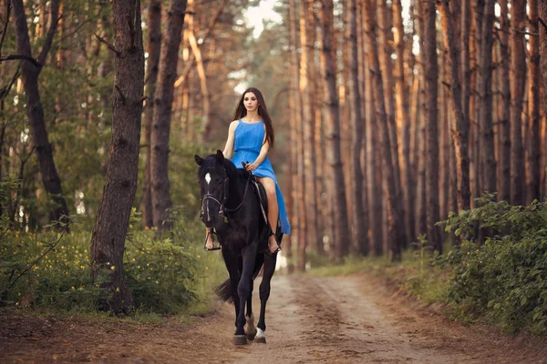 Mooie vrouw rijdt paard in bos — Stockfoto