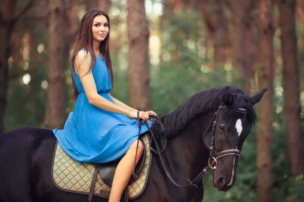 Mooie vrouw rijdt paard in bos — Stockfoto