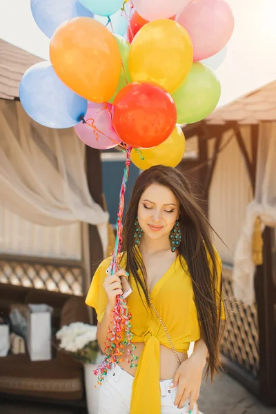 Beautiful young woman standing with balloons at wooden plank bed near pool — Stock Photo, Image