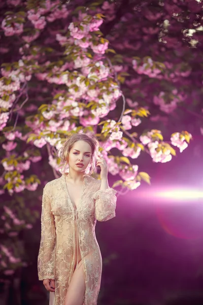 Bella giovane donna in piedi ad albero in fiore nel giardino — Foto Stock