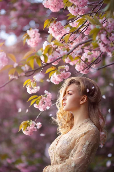 Menina adulta sexy bonita em pé na árvore florescente no jardim — Fotografia de Stock