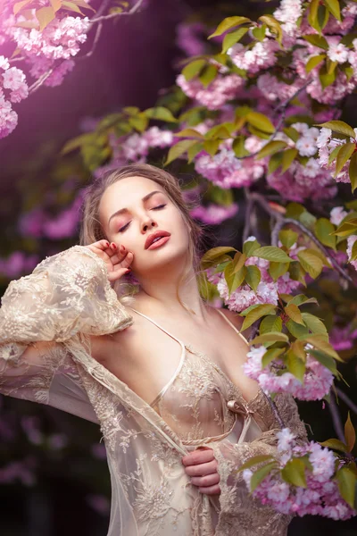Красивая сексуальная взрослая девушка, стоящая у цветущего дерева в саду — стоковое фото