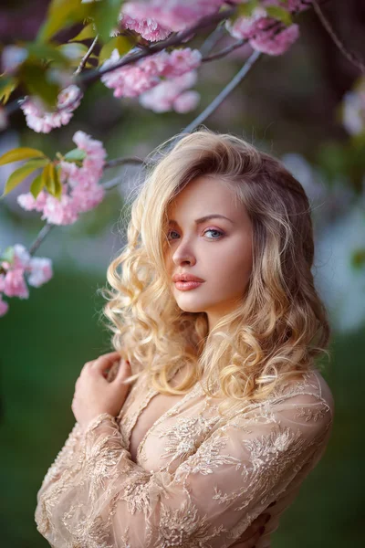 Mooi sexy volwassen meisje permanent op bloeiende boom in de tuin — Stockfoto