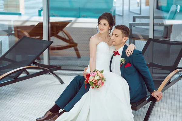 Bruid en bruidegom idoors bij het zwembad — Stockfoto