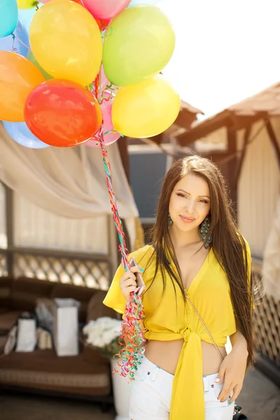 Bella giovane donna in piedi con palloncini a tavola di legno letto vicino alla piscina — Foto Stock