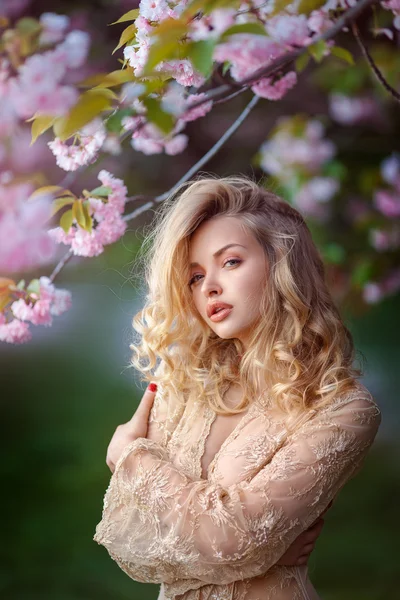 Vackra sexiga vuxna flicka står vid blommande träd i trädgården — Stockfoto