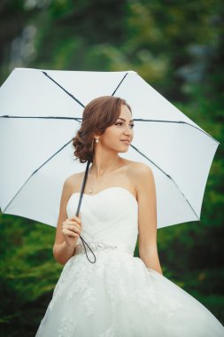 Beyaz şemsiye ile güzel gelin açık havada